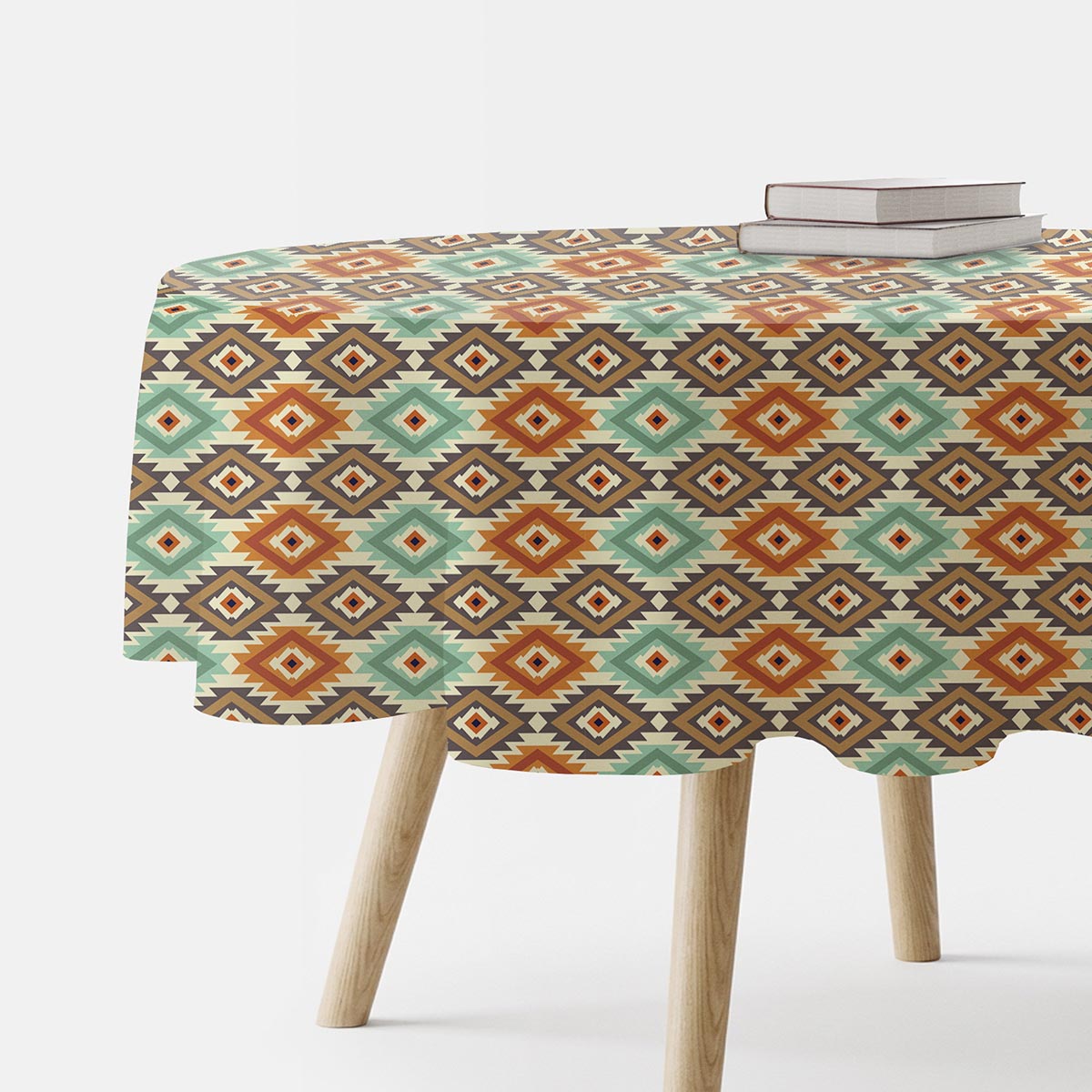 okrągły obrus na drewnianym stole z książkami, widoczny aztecki wzór miętowo-terakotowy