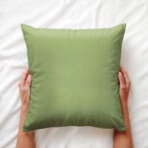 ręce trzymają miętową poduszkę dekoracyjną na pościeli, ujęcie z góry