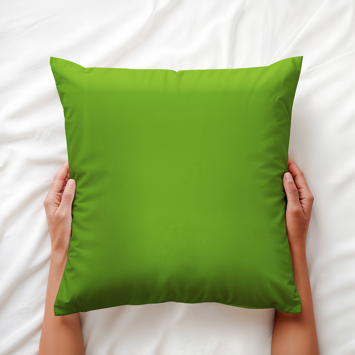 widok od góry z rękami trzymającymi zieloną poduszkę na pościeli