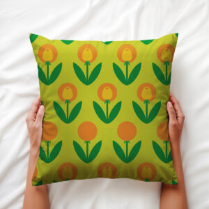 Poduszka trzymana w dłoniach, widoczny detal graficznych kwiatów i liści