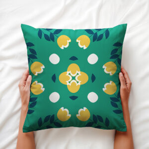 Osoba trzyma poduszkę z motywem gałązek i żółtych kwiatów na białej pościeli