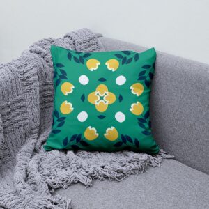 Poduszka z roślinnym wzorem na szarej kanapie obok pleda