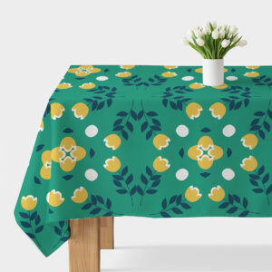 Obrus z zielonym tłem i żółtymi stylizowanymi kwiatami ustawiony na stole z białym wazonem i tulipanami