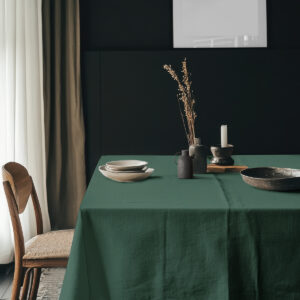 aranżacja stołu z talerzami i dekoracjami na zielonym obrusie