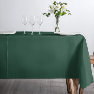 stół nakryty zielonym obrusem z kieliszkami i wazonem z kwiatami