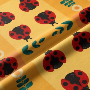 Zbliżenie tkaniny z czerwonymi biedronkami, zielonymi listkami i fakturą materiału