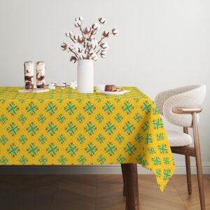 Stół udekorowany wazą i dodatkami na żółtym obrusie z motywem kwiatowym