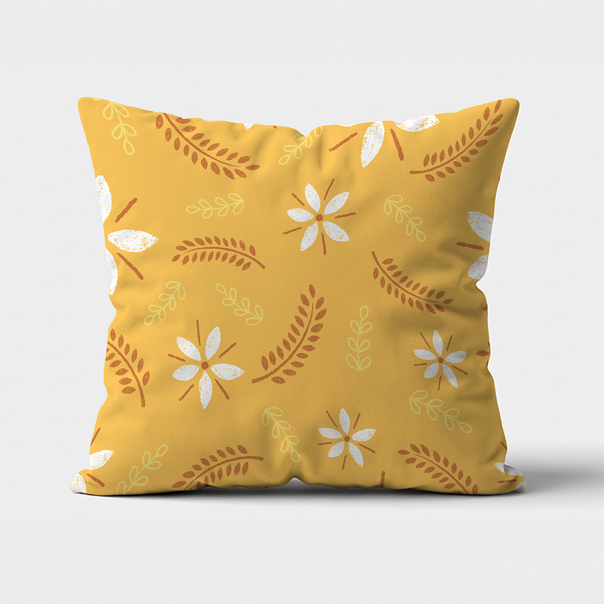 Główne ujęcie poduszki z musztardowym tłem, białymi kwiatami i brązowymi listkami