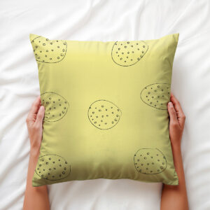 Widok poduszki trzymanej dłońmi, pokazujący rysunkowy motyw okręgów i miękkość materiału