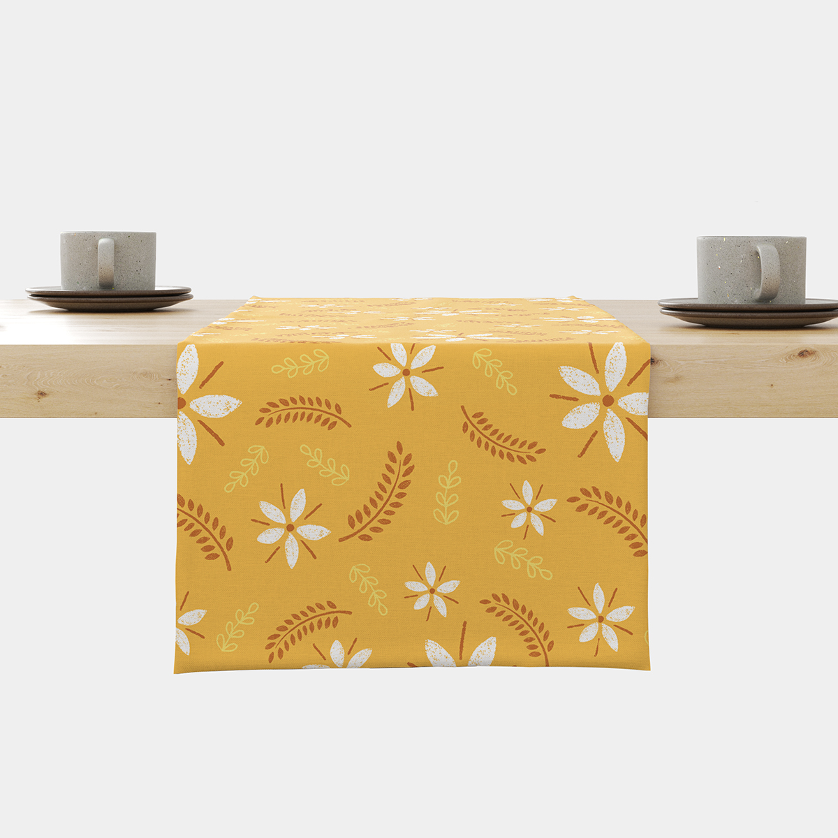 Bieżnik z musztardowym tłem i białymi, stylizowanymi kwiatami rozłożony na drewnianym stole z filiżankami