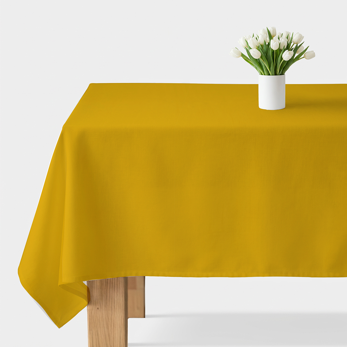 musztardowy gładki obrus rozłożony na stole z białym bukietem tulipanów