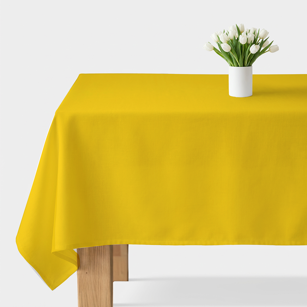 gładki żółty obrus na stole z białym wazonem i tulipanami