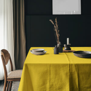aranżacja stołu z żółtym obrusem i ceramicznymi naczyniami na ciemnym tle