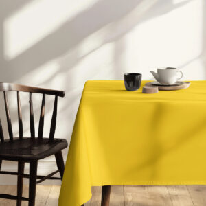 fragment stołu z żółtym obrusem i wygodnym siedziskiem przy oknie