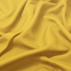 zbliżenie na gładką fakturę żółtej tkaniny obrusowej z delikatnymi załamaniami materiału