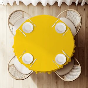 widok z góry na okrągły stół nakryty żółtym obrusem z ustawionymi nakryciami i zastawą