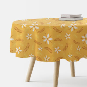 Okrągły obrus na stole z motywem białych kwiatów na musztardowym tle, widok z boku