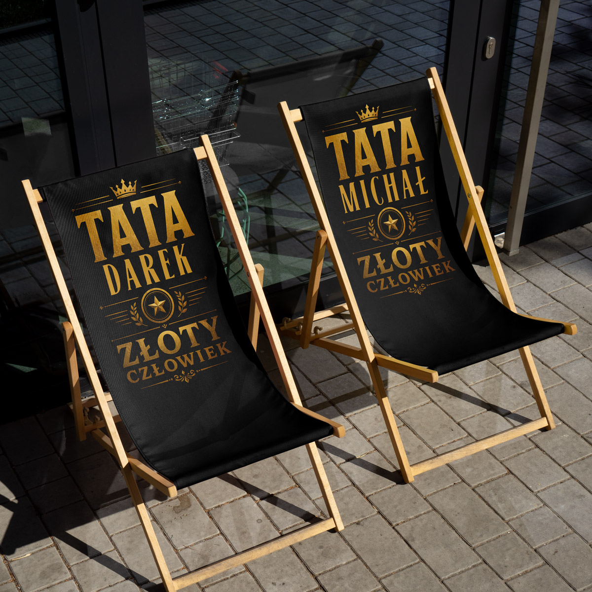 Zbliżenie na złoty nadruk „TATA” z imieniem na czarnym materiale leżaka — close-up personalizacji imienia idealny dla prezentu na Dzień Ojca.