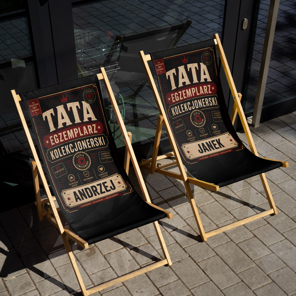Detal nadruku: retro typografia „TATA EGZEMPLARZ KOLEKCJONERSKI” na czarnym materiale leżaka — close-up personalizacji imienia dla taty